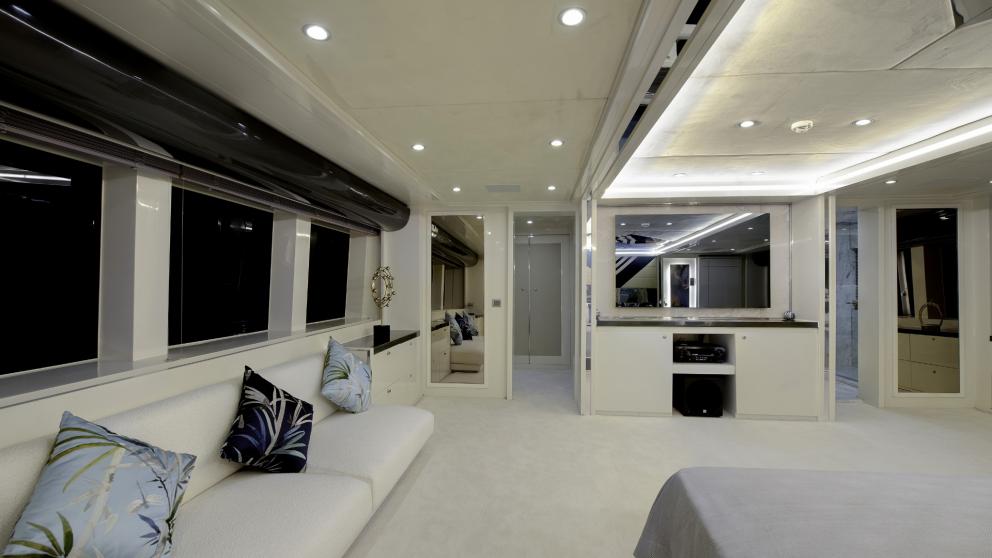 A seating area with decorative cushions in a spacious, brightly lit luxury yacht bedroom.